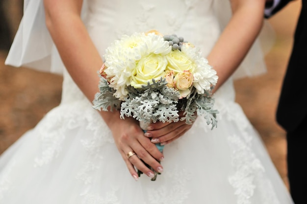 Bride holding white wedding bouquet of roses and love flower