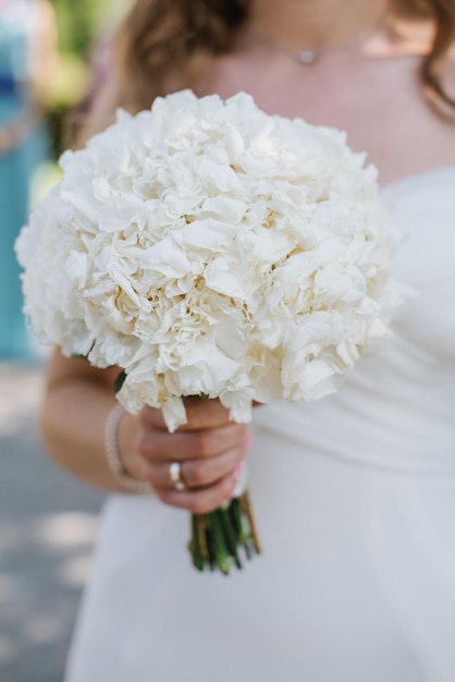 The bride holds a beautiful bouquet of white flowers Closeup view