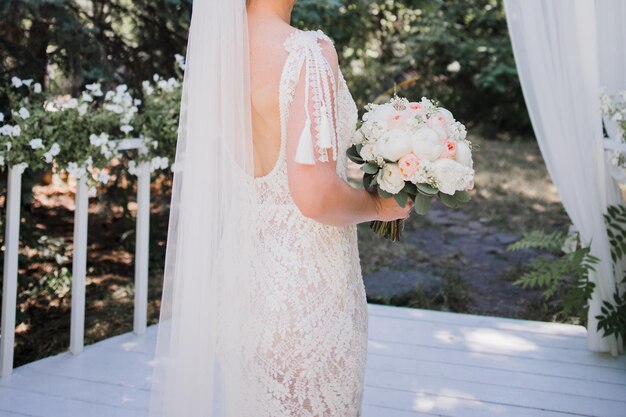 A bride holds a bouquet of flowers on a deck