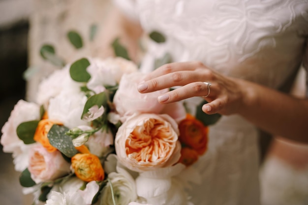 Bride holds a bouquet of multicolored peonies in her hands closeup