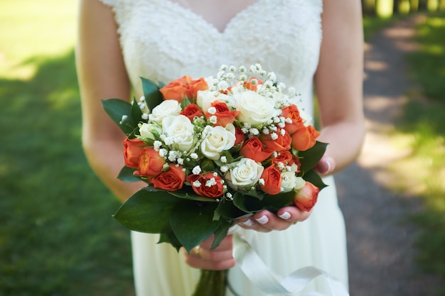 Bride holds a bouquet of orange roses