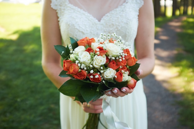 Bride holds a bouquet of orange roses