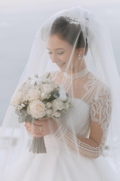 The bride holds a bouquet and poses during a walk in winter Exquisite dress and hairstyle