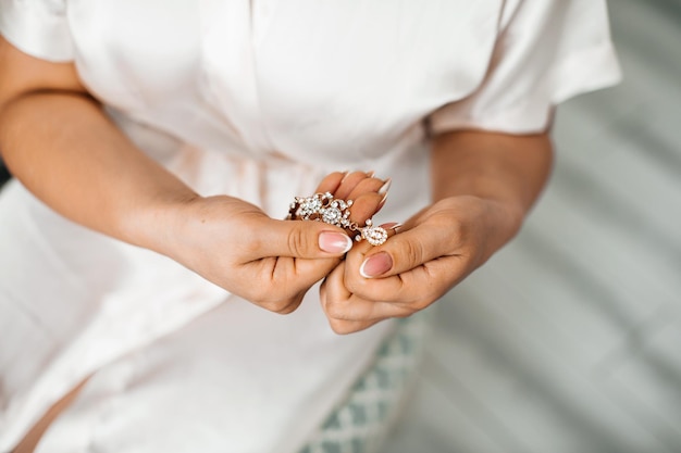 The bride holds earrings in her hands