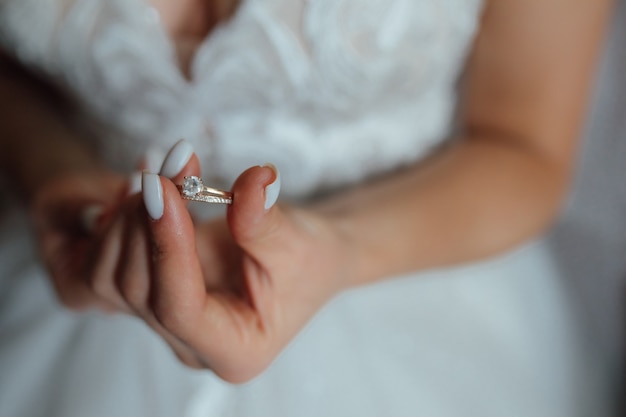 the bride holds a gold wedding ring with a diamond