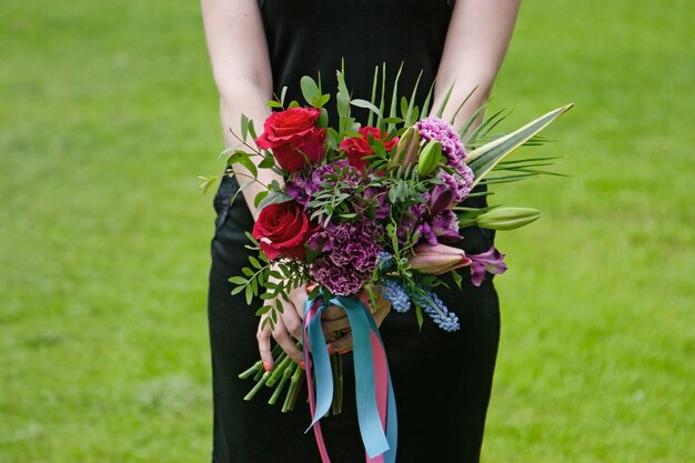 花嫁は結婚式のアクセサリーを手に持っています-バラで作られた花束