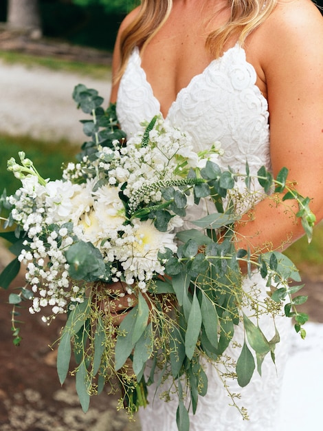 花嫁は結婚式のアクセサリーを手に持っています-バラで作られた花束