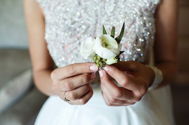 Bride holds little white boutonniere in her arms