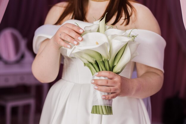 Foto la sposa tiene un bouquet di nozze nelle sue mani con uno sposo