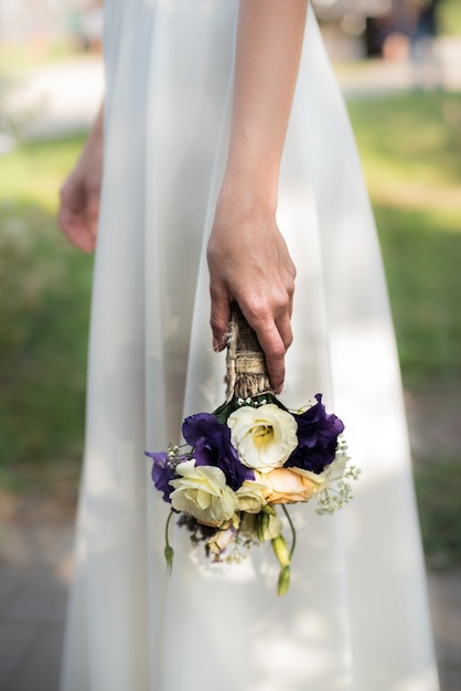 The bride holds a wedding bouquet with purple flowers