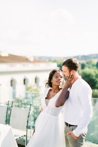 Bride hugs groom near the table on the roof of the building