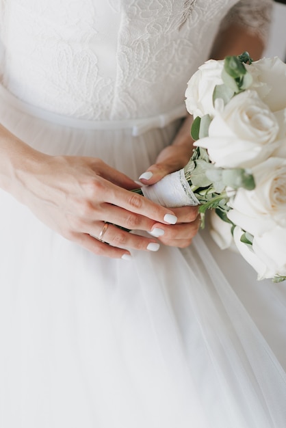 Фото Невеста в белом платье держит букет в день свадьбы
