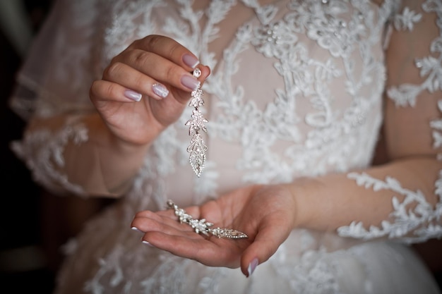 The bride is holding beautiful earrings in her hands 3168