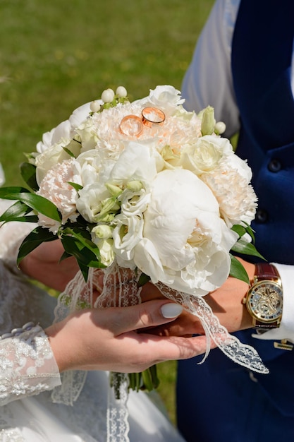 花嫁は新郎が近くに立っている花束を持っています