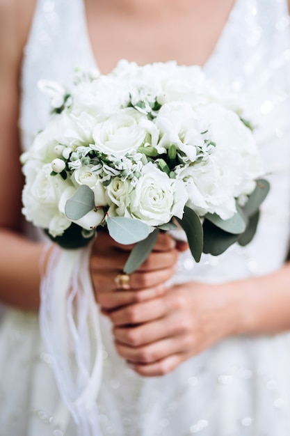 La sposa sta tenendo un mazzo di nozze. delicato bouquet da sposa nei toni del bianco e del lilla.