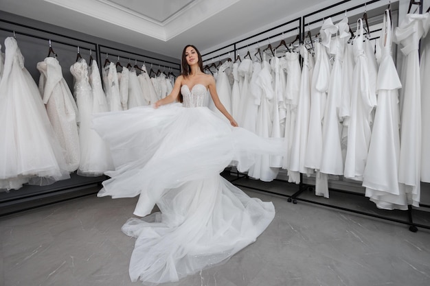 Photo bride is trying on a white wedding dress against the background of a large number of dresses