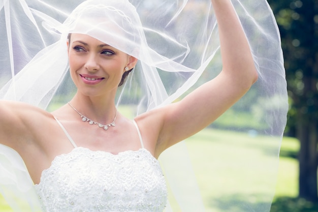 Bride lifting her veil in garden