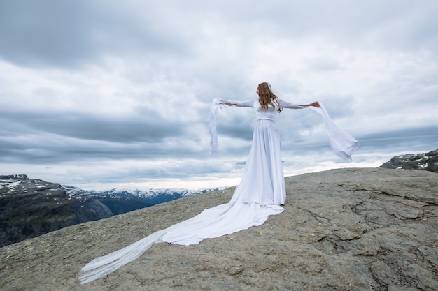 bride in a long wedding dress on a rock fragment in the mountains