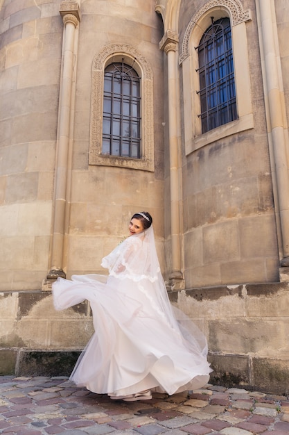 The bride looks into the camera and whirling near the church