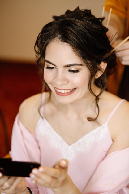 The bride looks in the mirror at her makeup in the morning when she is doing her hair