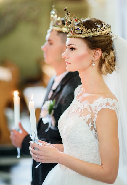 Невеста выглядит серьезной фигурой в золотой короне во время церемонии