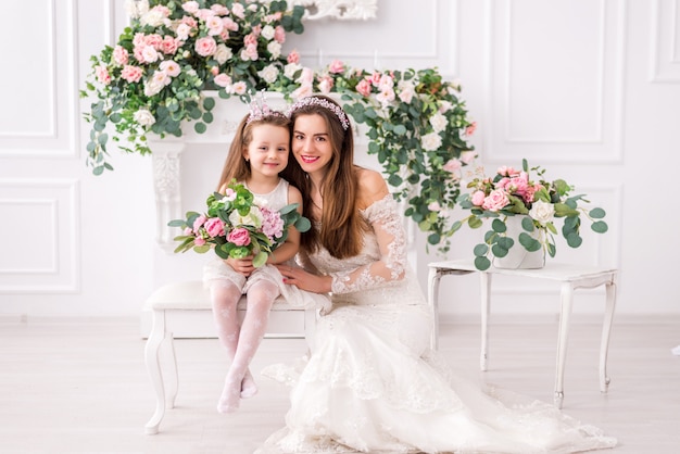 Bride mother and daughter in white dresses with flowers