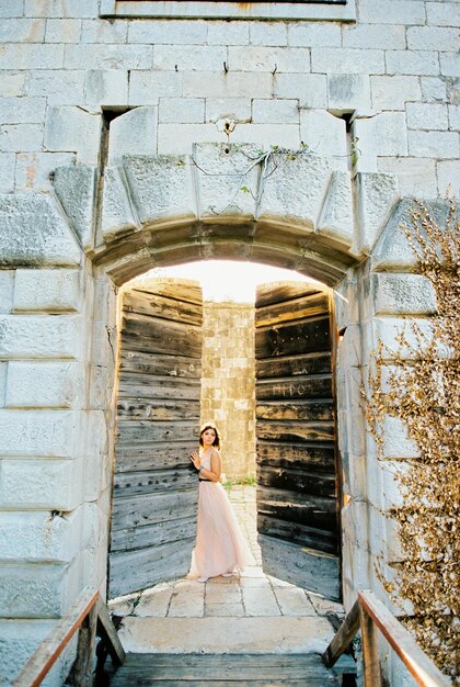 写真 花嫁は石の要塞の古い木製のドアを開ける
