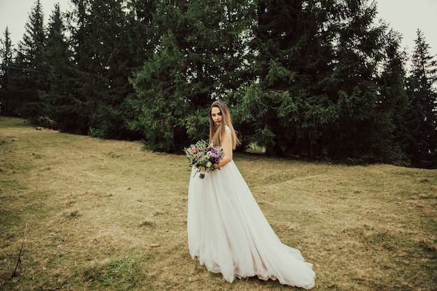 Bride in a pale rose dress walks along a mountain