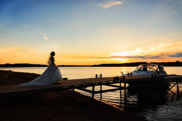 Bride on the pier by the river at sunset