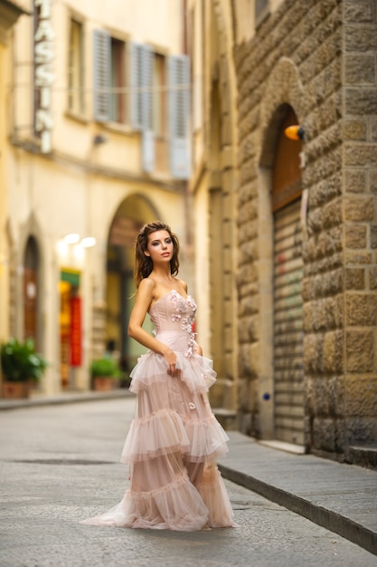 A bride in a pink wedding dress walks in Florence, Italy.