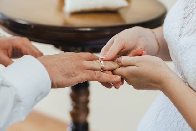 Bride puts a gold wedding ring on the finger of the groom