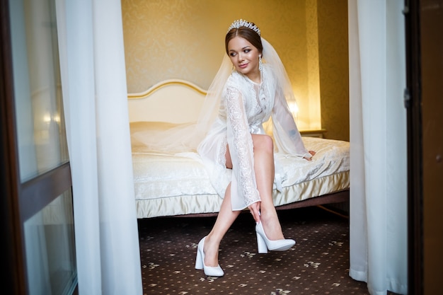 Bride puts on white shoes on the wedding day