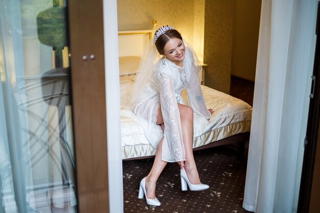 Bride puts on white shoes on the wedding day