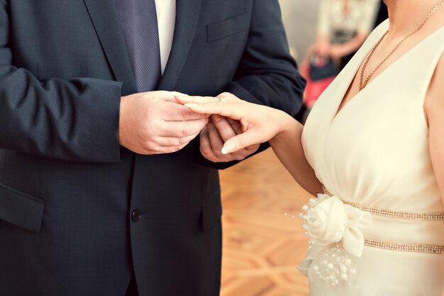 Bride putting a ring on groom's finger during wedding ceremony