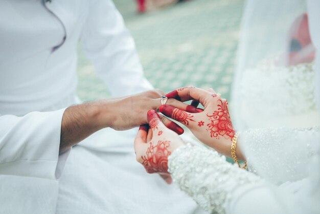 Photo bride putting ring on her husband hand