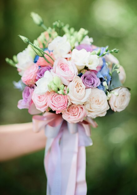 Bride reaches out her hand with wedding bouquet made of white and pink roses