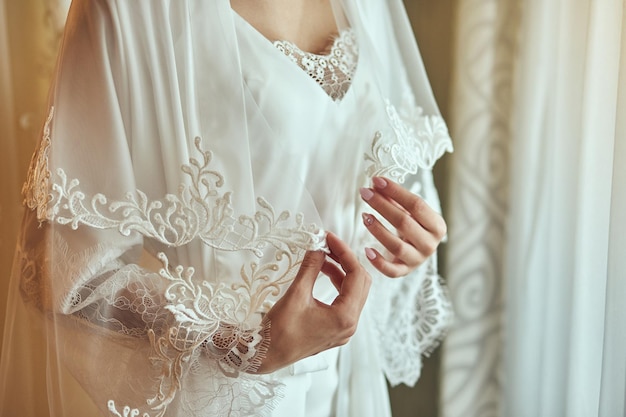 Sposa in un accappatoio vicino alla finestradonna che si prepara prima della cerimonia di nozze