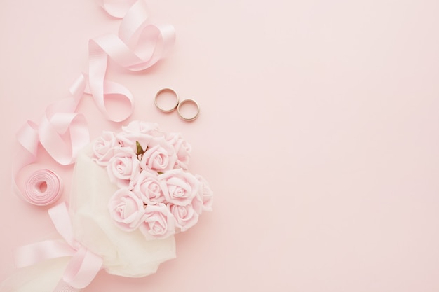 Bride's bouquet of pink roses, wedding rings and pink ribbon