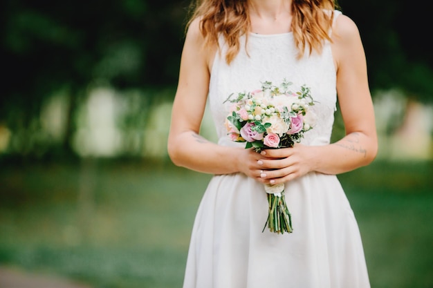 Photo bride's bouquet with white flowers. the bride holds a beautiful bouquet in her hands.