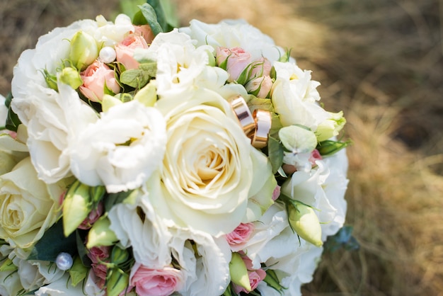 The bride's bouquet with white flowers and rings on the grass