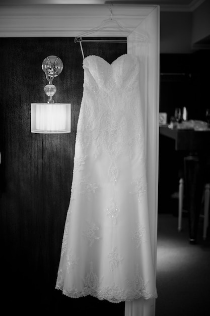 The bride's dress hangs on the black wall. bride's dress on a black wall, on a lamp. black and white