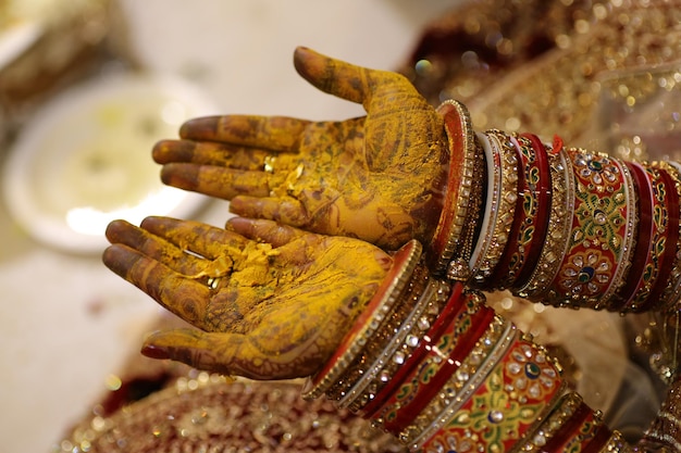 A bride's hands are decorated with gold paint and the words henna on the left hand.