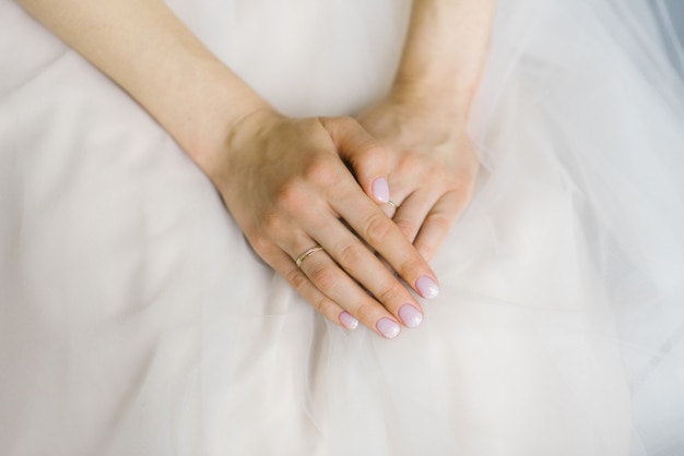 花嫁の手は折り畳まれ、ウェディングドレスに横たわっています