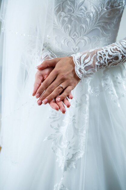 Le mani della sposa incrociate su un abito da sposa bianco