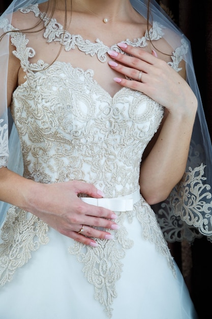 Le mani della sposa incrociate su un abito da sposa bianco