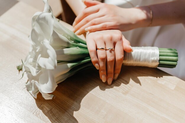 Foto le mani della sposa con un anello di fidanzamento appoggiato su un bouquet di gigli di calla bianchi