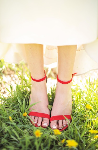 A bride's red sandals are shown in a field of grass.