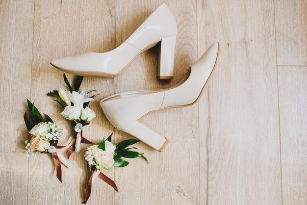 Photo bride's shoes with buttonhole on the wooden background, flatlay