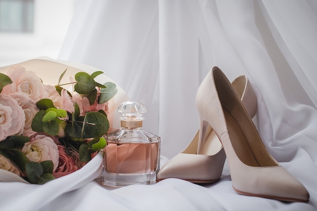 A Bride's shoes with a wedding bouquet and perfume on the veil. Wedding Concept