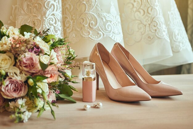 Bride's wedding accessories such as high heel shoes bouquet earrings and perfume